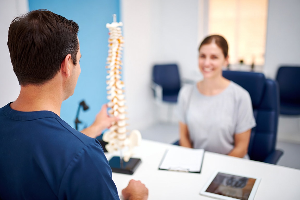 Chiropractor explaining a treatment plan with a spine model at Smiley Chiropractic in Garland, TX